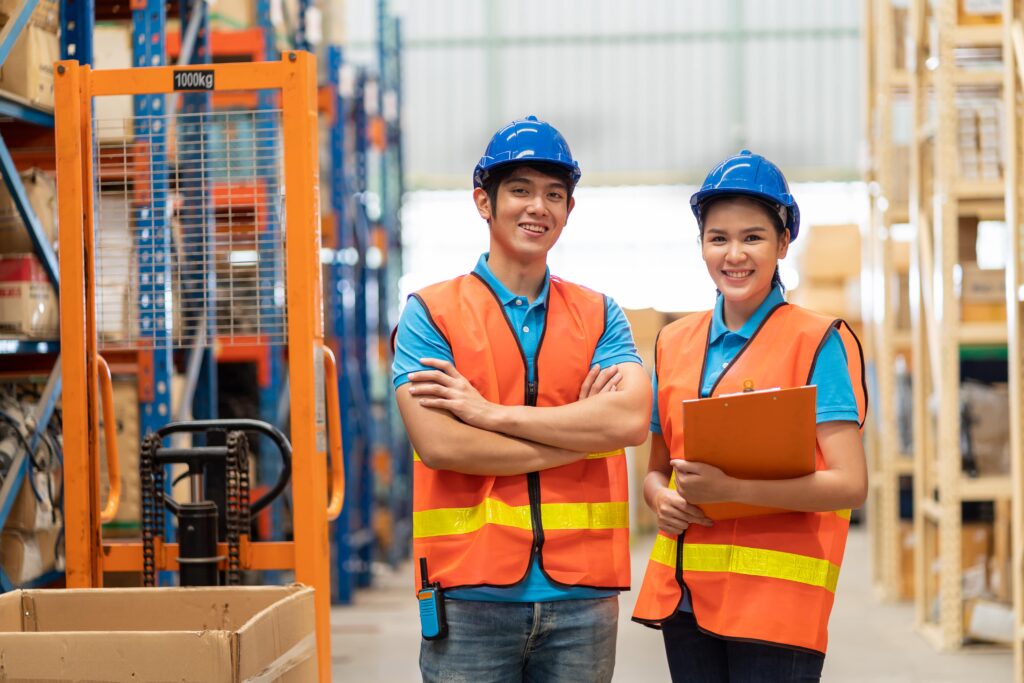 warehouse workers in safety vest and helmet standing with arms crossed
