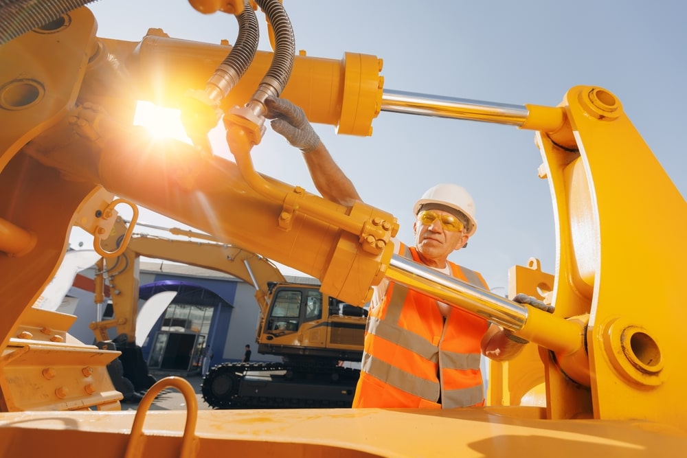 tractor mechanic checks hydraulic hose system equipment on excavator