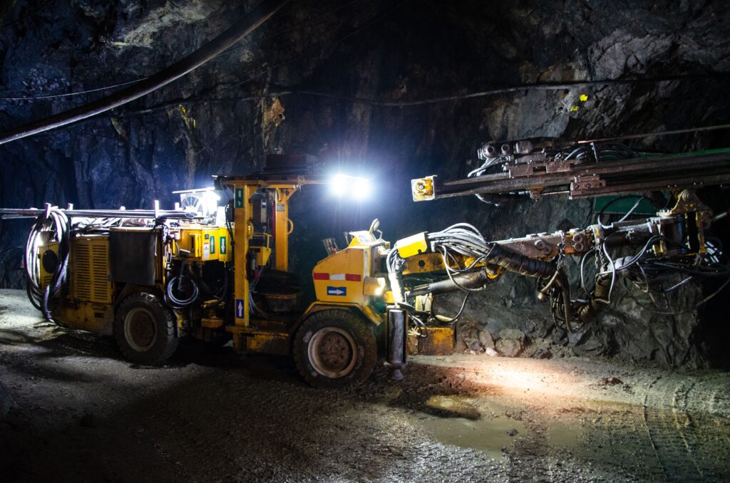 Heavy drilling machinery at work in a dimly lit underground mine