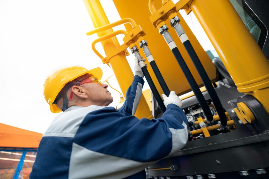 Machinery tractor mechanic checks hydraulic hose system equipment on excavator